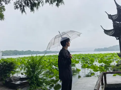雨天撑着透明雨伞站在绿地旁的人